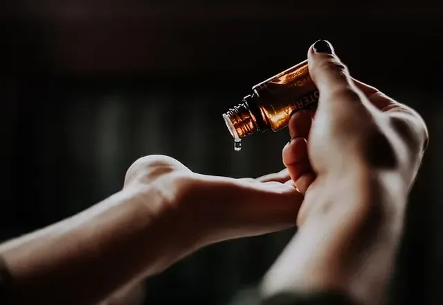 Huile essentielle versée dans la paume de la main avant un massage intuitif
